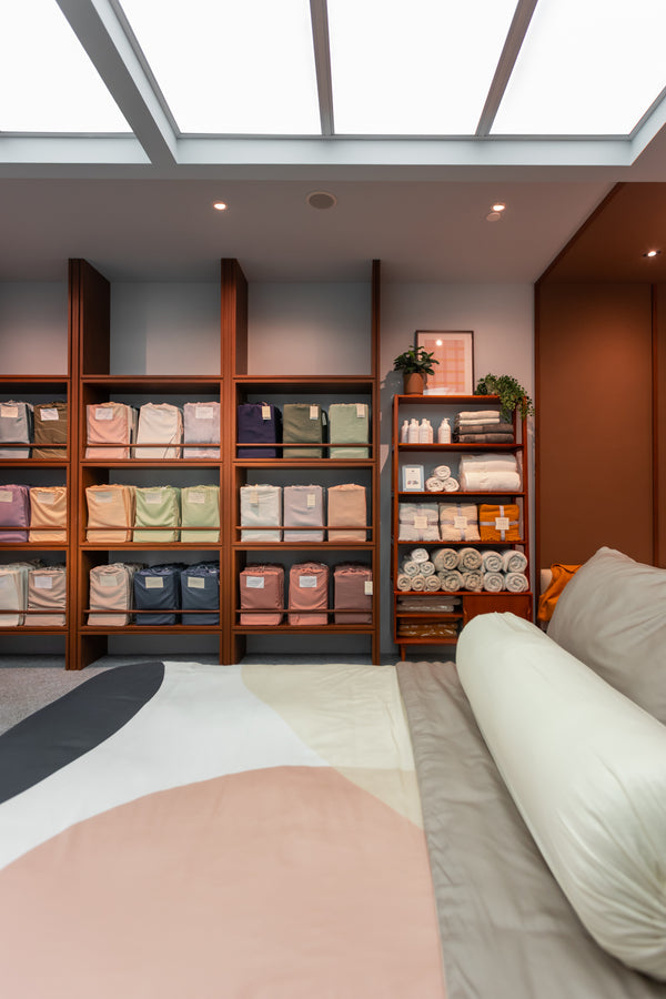 Bedding store featuring a display bed and shelves of bedding stock