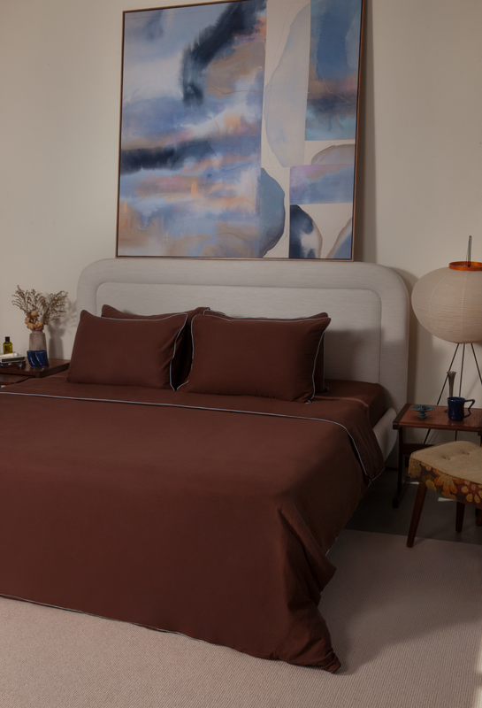 Brown bedspread on a bed with abstract art in the background